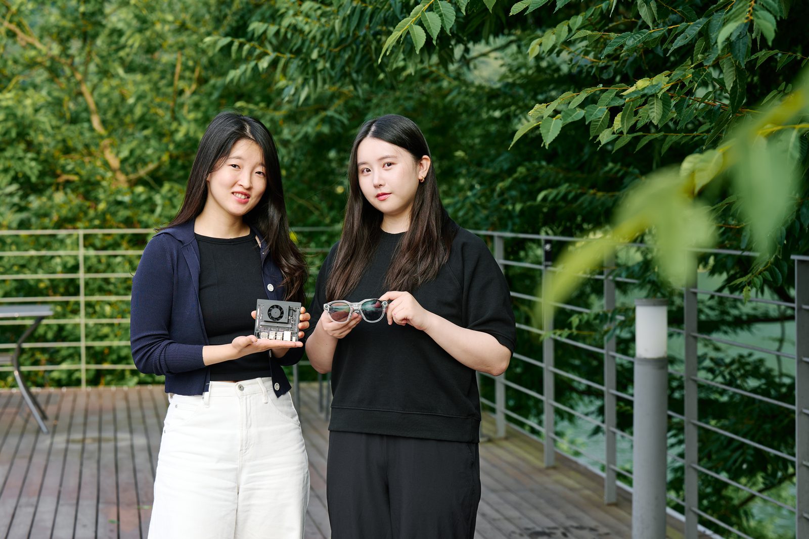 야외 데크에 선 두 공동대표. 왼쪽 정진서랑은 손바닥만 한 연산 보드를, 오른쪽 이주연은 AI 안경을 들고 있다.